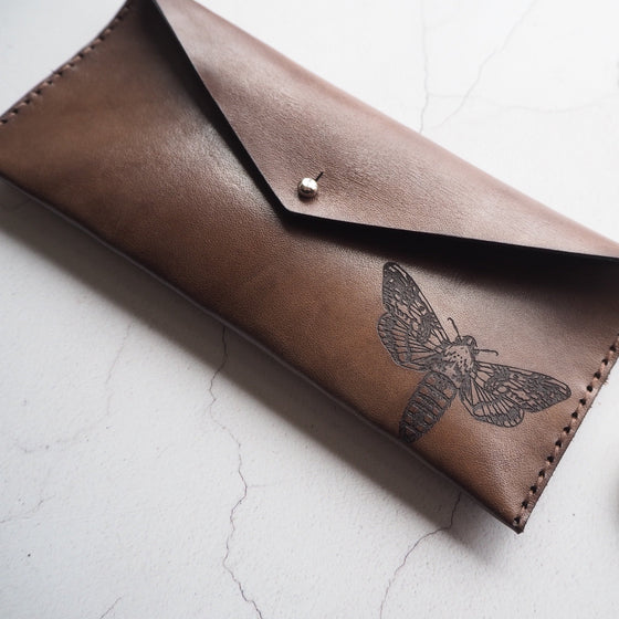 This slim leather pencil case features an engraving of our Moth design. 