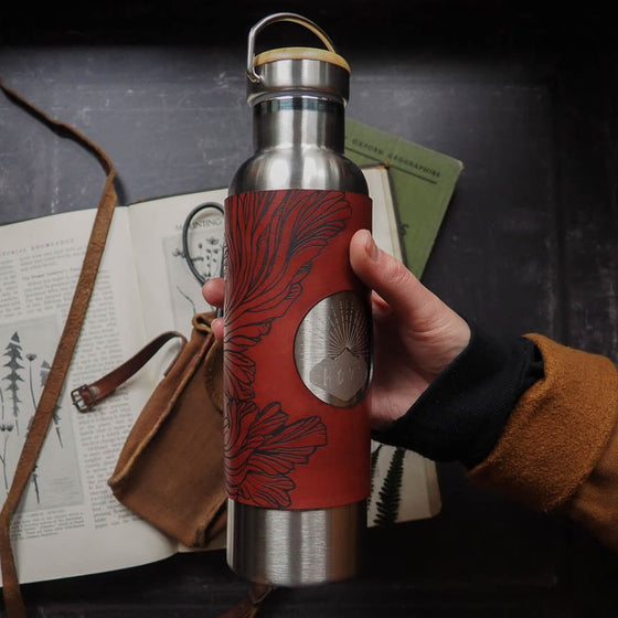 Mushroom Water Bottle - Stainless Steel 600ml. The leather wrap is engraved with a detailed illustration that explores the paterns of the frills of the splitgill mushroom. The leather wrap is dyed in burgundy. by Hord.
