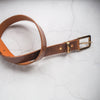 This tan leather belt has been handcrafted with thick pull up leather along with a solid brass hardware.
