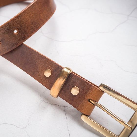 Closer look at the solid brass hardware of the tan leather belt.