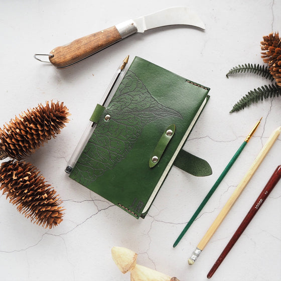 An A6 leather notebook cover that's been hand dyed in green leather colour and hand stitched in light brown stitch colour. 