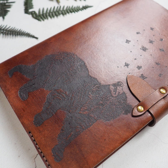 Close-up of the illustration of the Bear & Butterfly engraved leather notebook featuring an engraving of a Bear and butterflies.