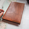 The topography journal cover that has been hand dyed in brown leather colour and hand stithed in yellow stitch colour.
