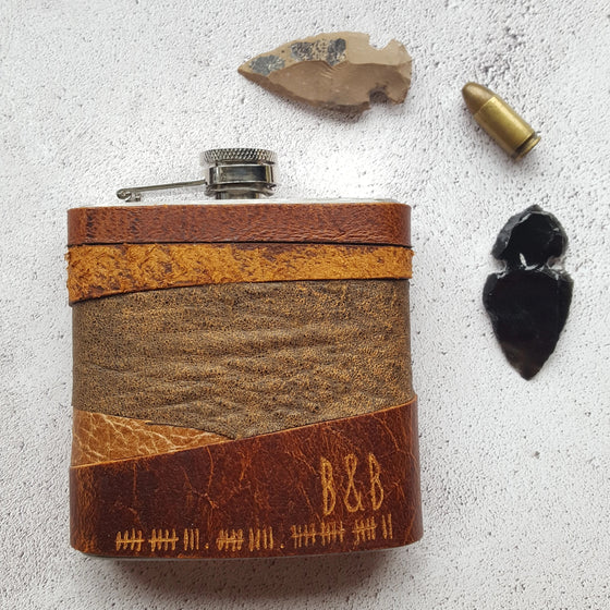 This rum hip flask has been leather wrapped with varying leather pieces onto a stainless steel flask showing a rugged look.