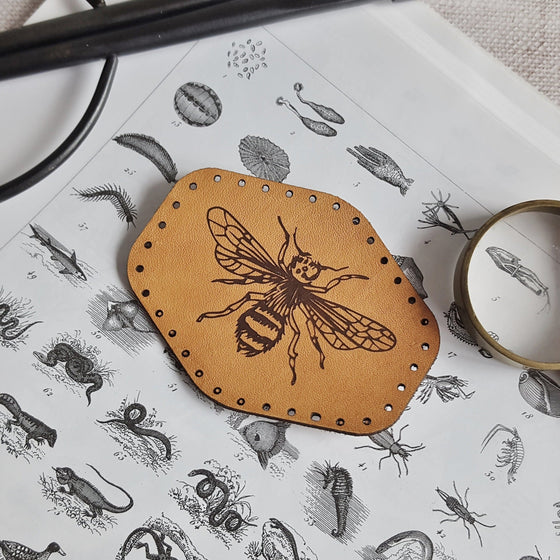 This rounded hexagonal leather patch is hand dyed in a tan colour and engraved with the illustration of a bee - a great gift for those who appreciate bees and everything they do for us, or insects in general. The Bee Journal from Hord.