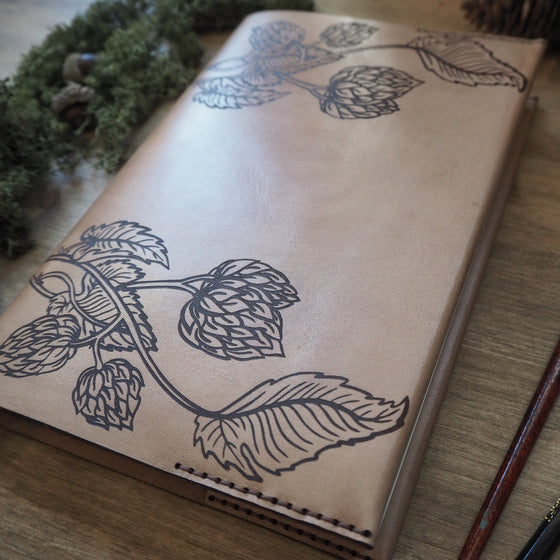 Close-up view on the engraving of hop flower and leaves on a camel coloured Beer Journal by HÔRD.