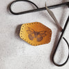 This hand dyed tan leather patch is engraved with an illustrative butterfly and has pre-cut stitch holes to make sewing easy. The butterfly patch from Hord.
