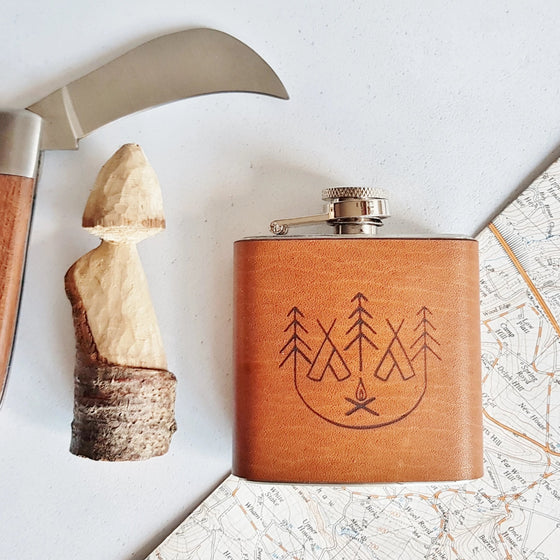 This camping hip flask has been hand crafted using luxurious European leather and engraved with the illustration of a camp fire.
