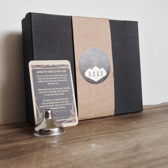 The Coordinates Leather Flask is wrapped up in a gift bag with a funnel and care instructions all ready for gifting.