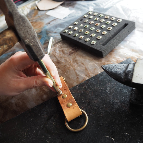 Initials being stamped onto the Dyrr Leather Key fob, a leather keyring from HÔRD.