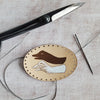This natural leather goose patch is engraved and hand painted with a hand shadow puppet of a goose. 