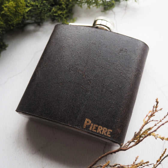 This monogrammed hip flask is made from a dark leather that clad onto a stainless steel hip flask.