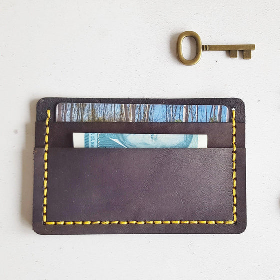 This handmade leather card holder has been hand stitched in yellow waxed linen thread.