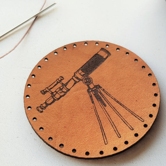 A close up picture showing the lovely texture of the engraved victorian telescope on this circular leather scientist patch. A perfect gift for people who find themselves filled with wonder at the thought of space and it's unknown expanse.