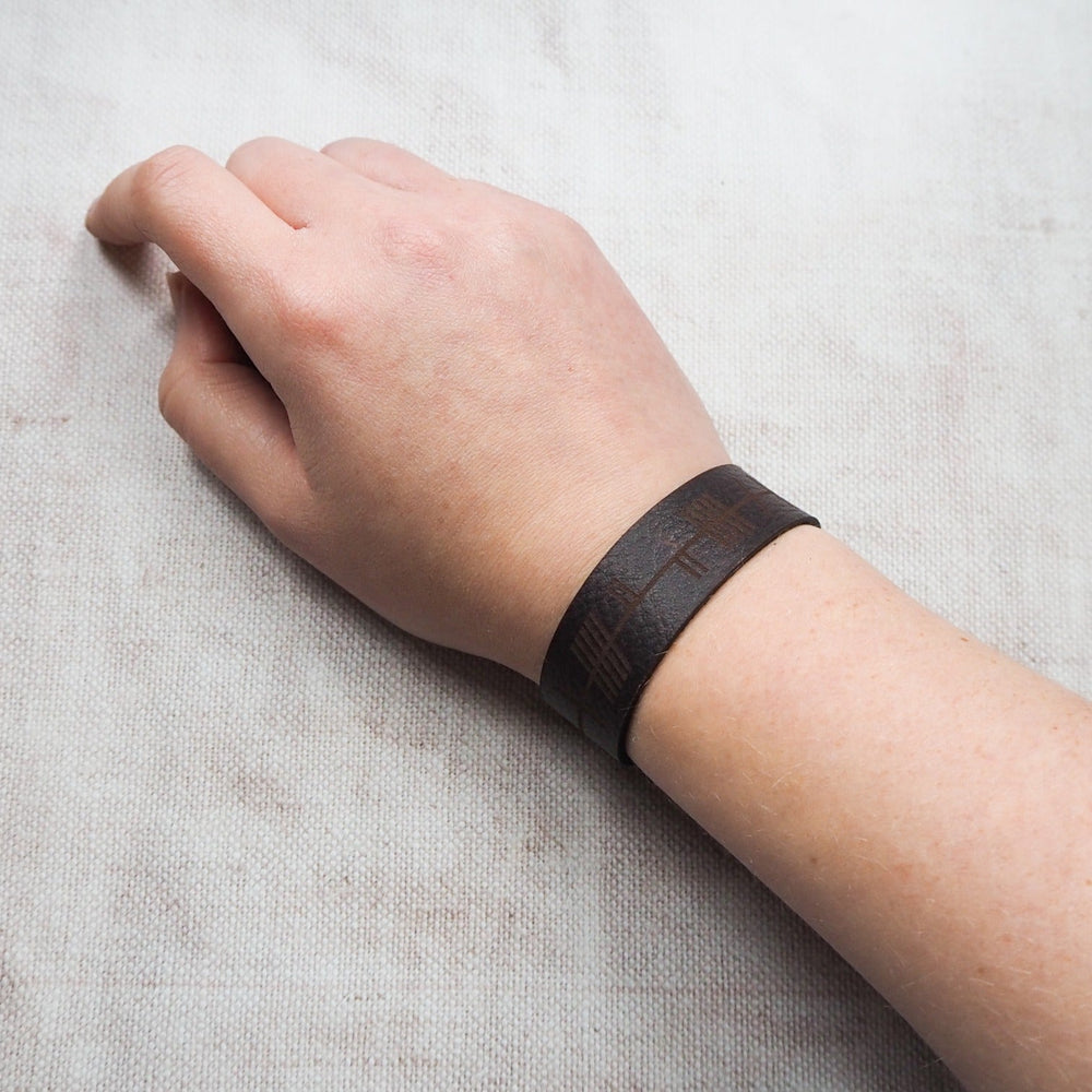 
                  
                    The Ogham Leather Cuff by HÔRD wrapped on a person's arm.
                  
                