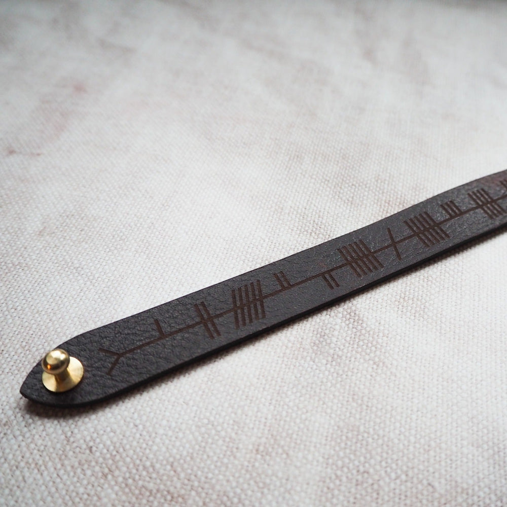 
                  
                    The Ogham Leather Cuff by HÔRD featuring the custom ogham text engraving.
                  
                
