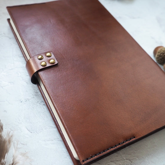 The leather notebook cover is hand stitched with dark brown waxed linen thread.