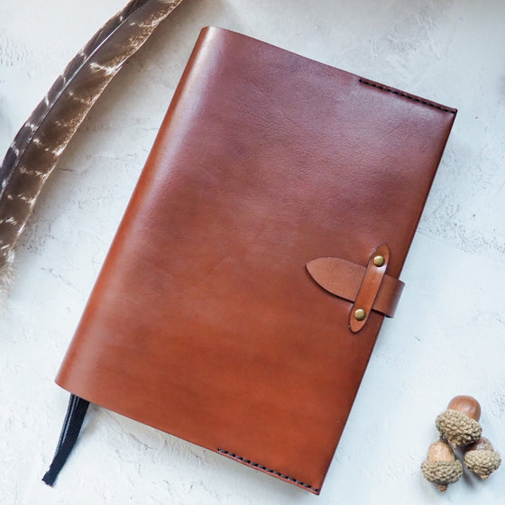 This leather notebook cover is hand dyed in light brown leather colour and fastened with a clasp.