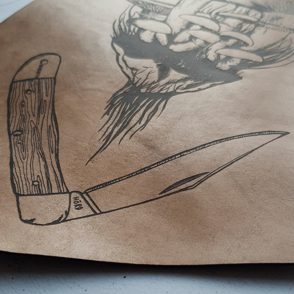 
                  
                    A close up of the Forager Banner by HORD, showing the details of the opinel style knife illustration. A great leather gift for those who love to spend their time outside in the woods foraging for mushrooms. The perfect leather wall decoration for your home.
                  
                