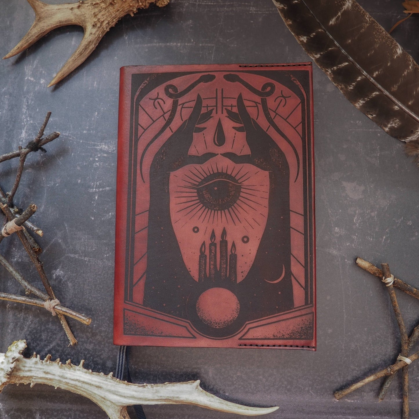 The Spell book leather journal cover featuring engravings of snakes, hands, candles, and more by HÔRD.